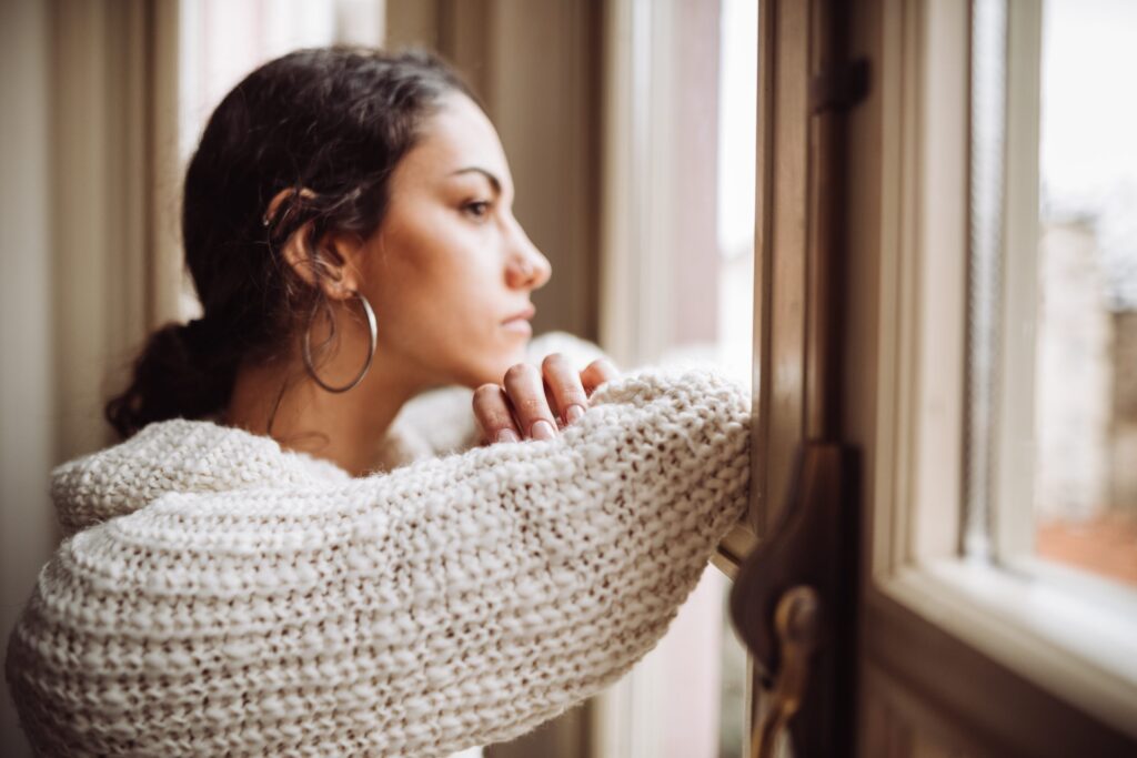 A young woman looking out a window contemplatively